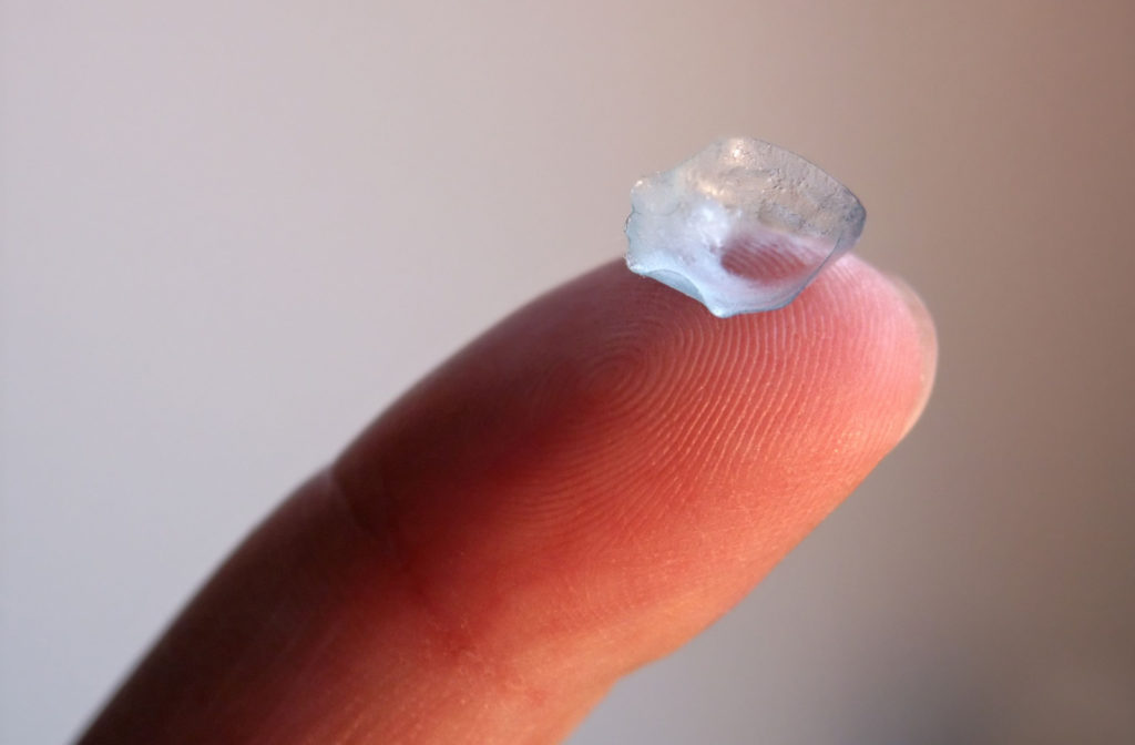 A close-up of a worn and dirty contact lens on a finger.