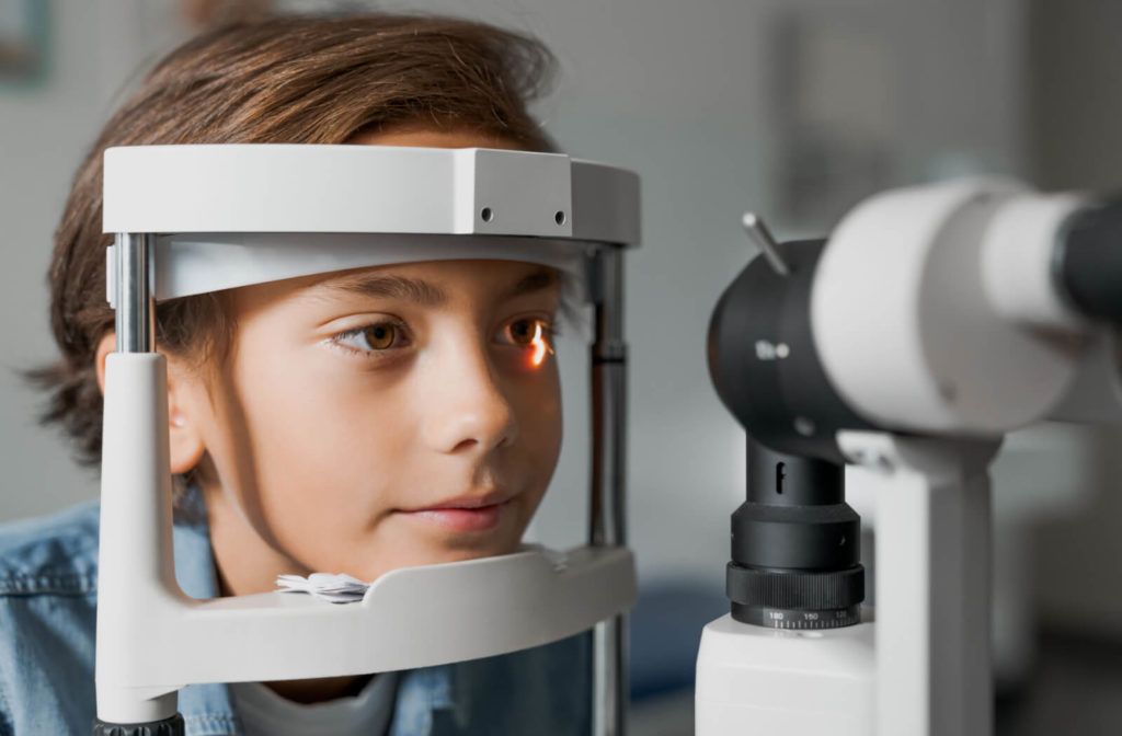 Close-up of a young boy looking into a machine that tests his vision.