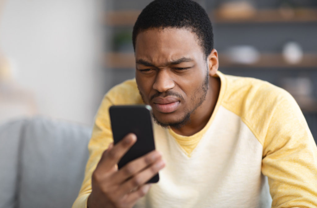 A man squinting to see his smartphone
