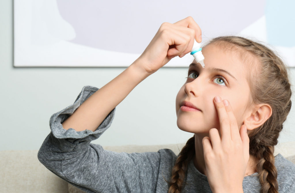 A young girl administering atropine eye drops as a form of myopia control to help slow the progression of her nearsightedness.