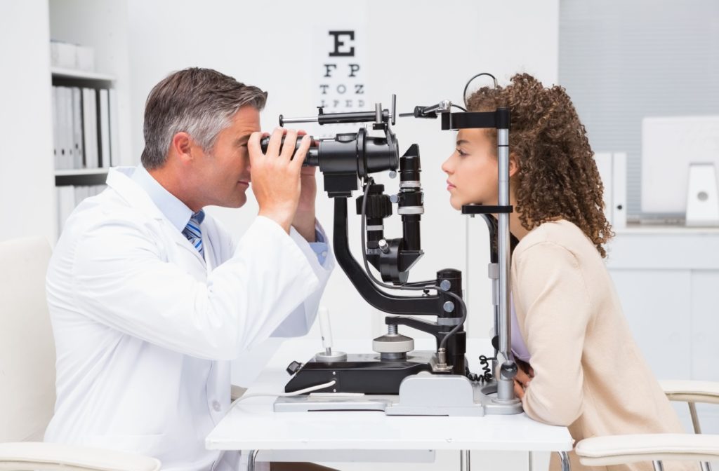 A male optometrist examines a female patient's eyes in an optometry clinic.