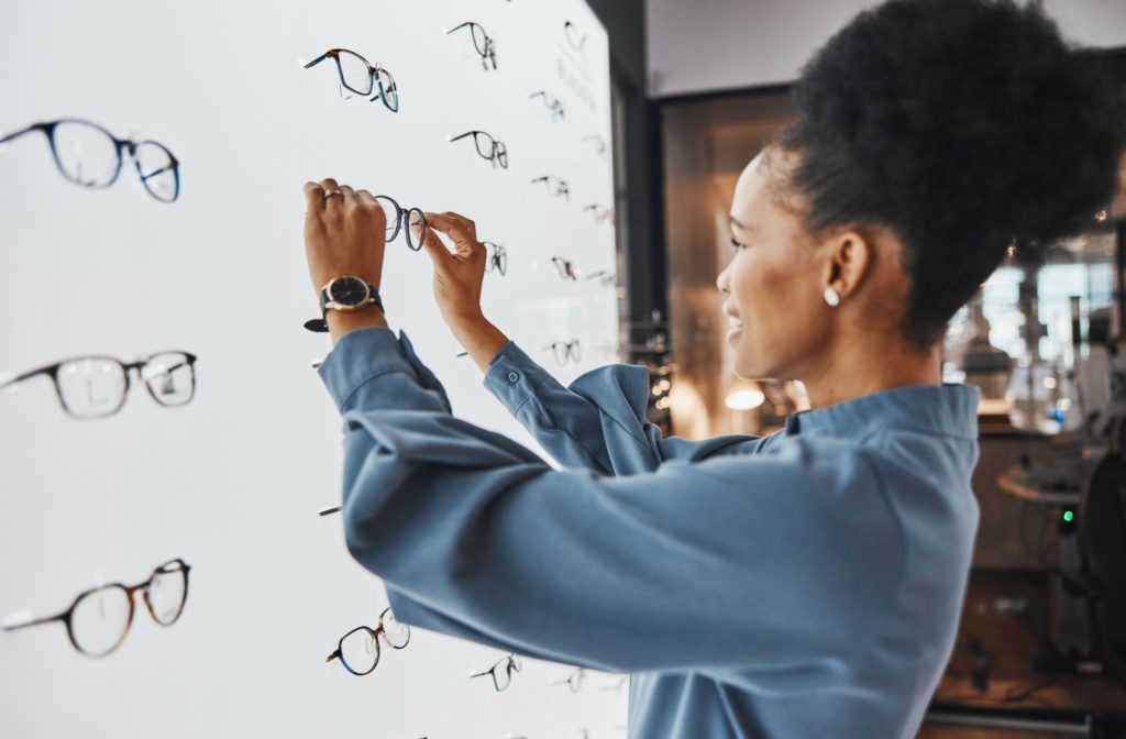 Woman selecting eyeglasses from a display in an optical store.