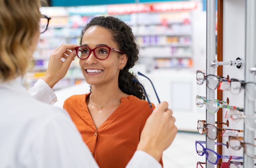 An optometrist helps a patient try on her new prescription glasses