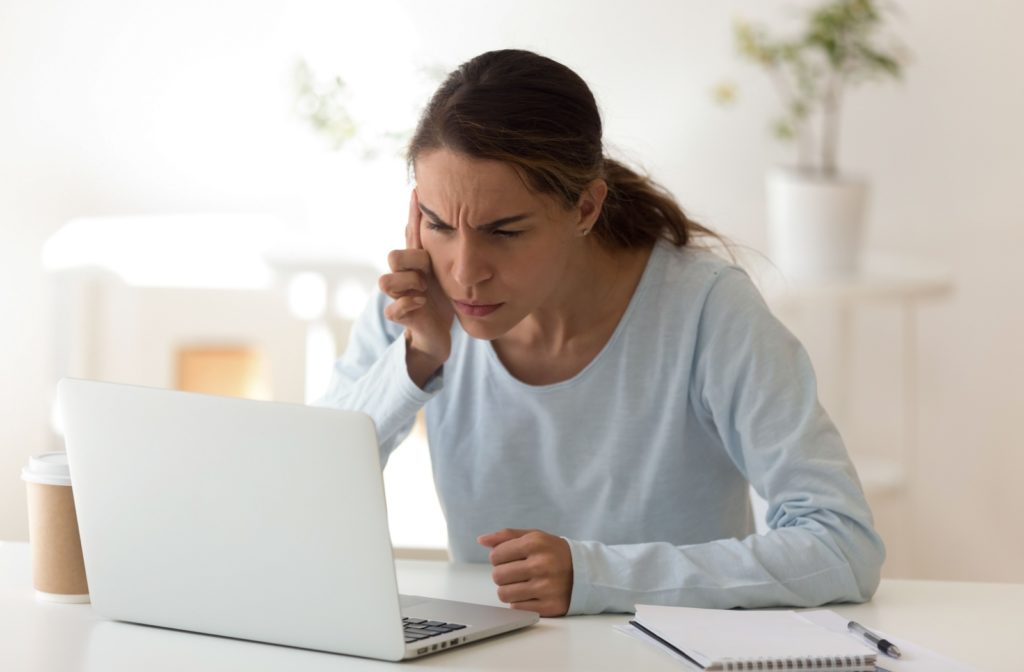 Woman squinting at her laptop screen.