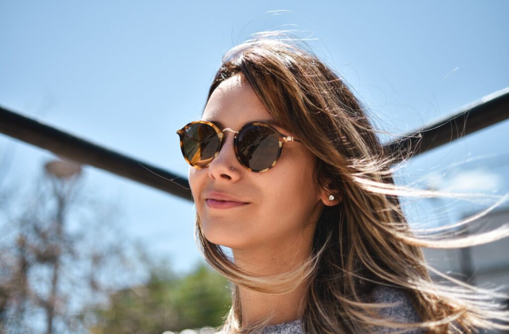 Someone wears stylish sunglasses outside to protect their eyes from UV rays.