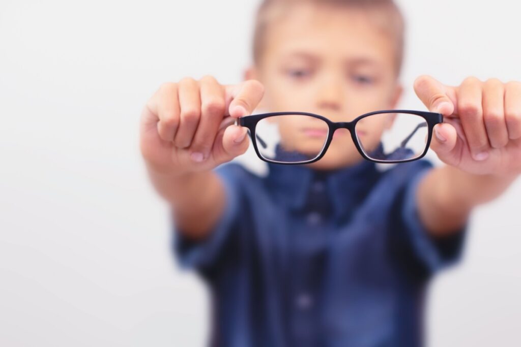 A kid holding out a pair of glasses to help correct their myopia.