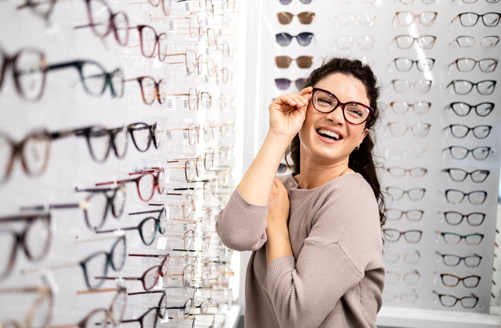 A person smiling, trying on a pair of glasses with lenses that correct their vision.